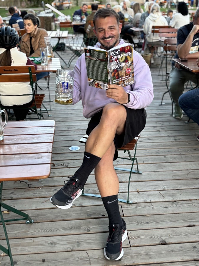 Coach Sepp liest im Biergarten sein Kochbuch